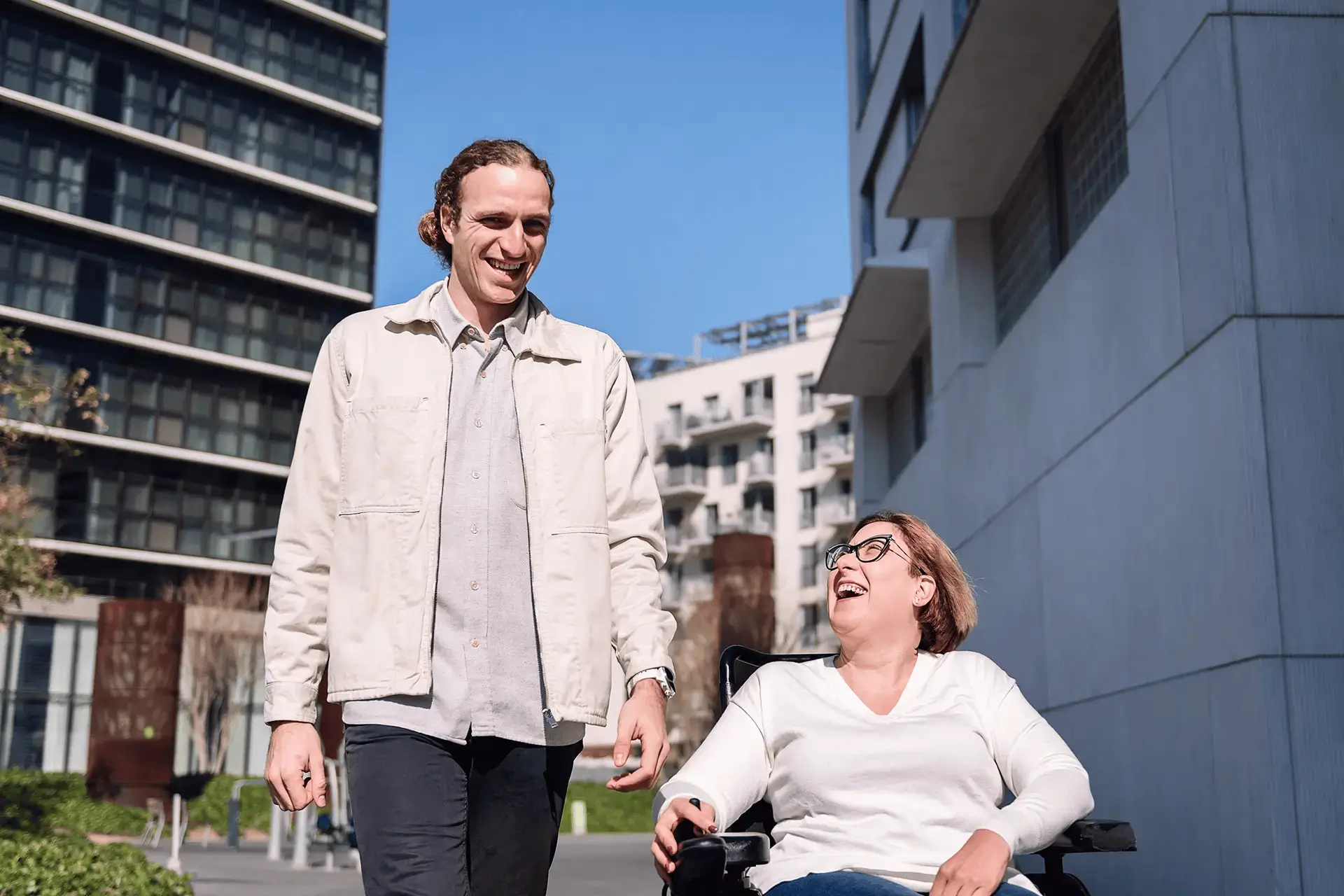 Two people smiling and talking, one using a wheelchair.